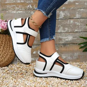 Sandali sportivi da donna bianchi e neri con cinturini in velcro indossati ai piedi