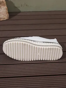 Detailed macro view of white platform sneaker sole featuring elegant silver chain trim