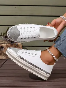 Detailed view of white platform sneakers with rhinestone toes and unique braided sole