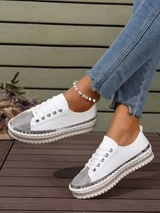 Close-up of white fashion platform sneakers featuring silver glitter toe caps and woven trim
