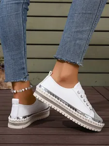 Side view of stylish white low-top sneakers with silver metallic and rhinestone details.
