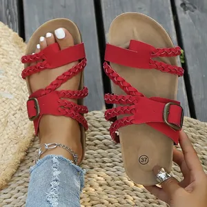 Detailansicht roter geflochtener Riemchensandalen mit Bronzeschnallen auf Matte