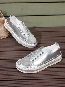 Metallic silver platform sneakers with rhinestone-encrusted toe and thick stitched soles.