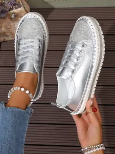 Close-up detail of stylish silver platform sneakers featuring sparkling rhinestone toe box ornaments.