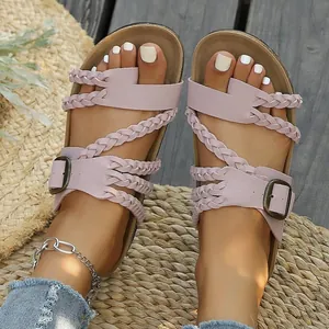 Nahaufnahme eleganter rosa geflochtener flacher Sandalen mit Metallschnallen am Fuß