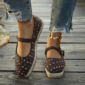 Close-up view of stylish brown studded Mary Jane flats with a woven espadrille sole edge