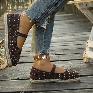 Close-up detail of brown suede Mary Jane flats with decorative gold studs and jute sole