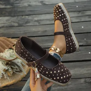 Macro view of brown suede Mary Jane flats featuring gold studs and espadrille soles