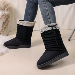 Close-up of black fashion boots featuring knitted shaft with cream lace and bow detail.