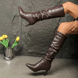Side view of elegant brown slouched knee-high boots with pointed toe and stiletto heel