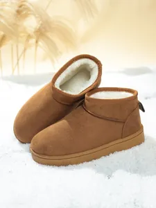 Classic brown suede snow boots with soft white faux fur lining on a snowy surface