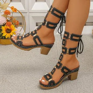 Detail shot of black gladiator block heel sandals with gold buckles and laces.