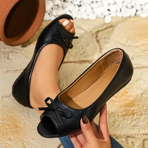 Close-up of black peep-toe ballet flats featuring a decorative bow detail