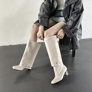 Detail view of stylish cream high boots featuring metal studs and transparent heels