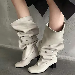 Detailed view of stylish off-white slouchy mid-calf boots with metallic stud details