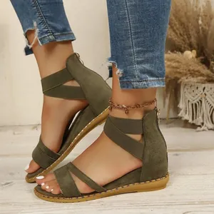 Close-up detail of olive green flat sandals featuring cross straps and metallic stud trim
