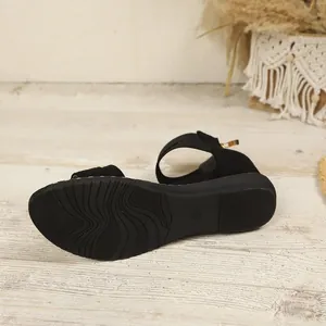 Detailed view of the black suede sandal's anti-slip rubber sole with wavy patterns.