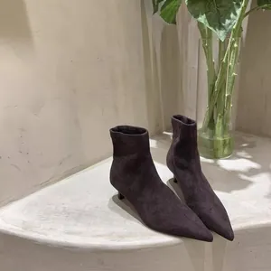 Detailansicht eleganter dunkler Wildleder-Stiefeletten mit modischem Pfennigabsatz.