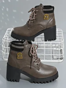 Detailed view of brown lace-up chunky heel boots with knit collar and metal badge