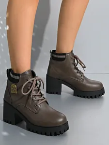 Stylish brown lace-up chunky heel ankle boots featuring a vintage metal cross emblem detail.