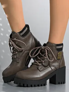 Detailed view of stylish brown chunky heel ankle boots with knit collar and metal crest