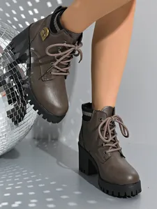 Detailed view of stylish brown lace-up ankle boots with chunky heel and bee charm