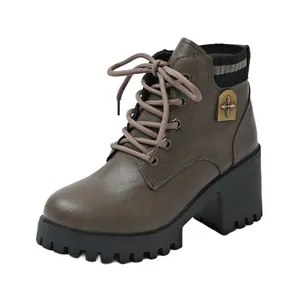 Detail view of brown lace-up ankle boots with a decorative star emblem and block heel.
