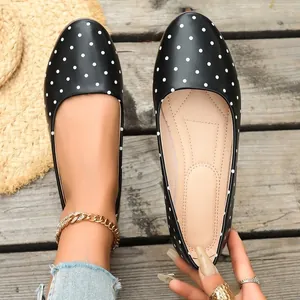Vista dall'alto di eleganti ballerine nere a pois bianchi su tavole di legno rustico