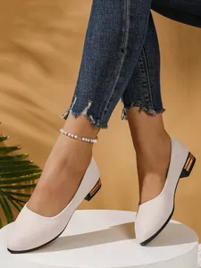 Elegant pointed toe cream knit flats with decorative gold striped block heel worn with denim