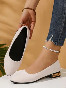 Detail view of beige pointed-toe flat shoes with gold-accented heels and soft texture.