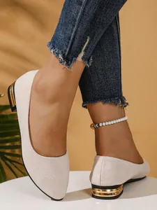 Close-up detail showing the elegant cream textured ballet flats with gold metallic heel trim