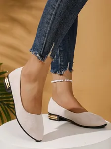 Detail of beige low block heel flats with elegant gold metallic accents on the heel