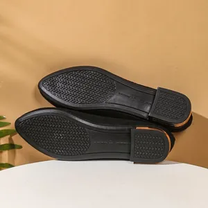 Detail of anti-slip rubber sole and gold heel accent on black pointed-toe ballet flats