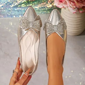 Detailed view of silver sparkly pointed toe flats featuring a large glittery bow
