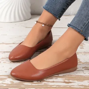 Detailed view of stylish brown pointed-toe flat shoes worn on feet with a pearl anklet