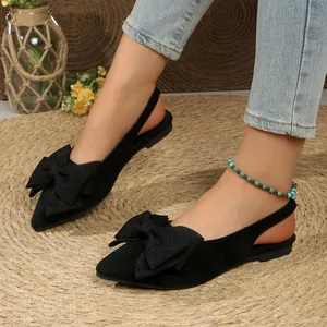 Détail de chaussures plates slingback noires à bout pointu avec un grand nœud brillant