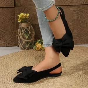 Flats slingback noires élégantes à bout pointu avec nœud papillon sur un tapis tissé