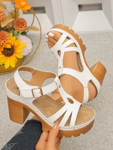 Detailweergave van witte platformsandalen met blokhak in houtlook en een T-bandje.