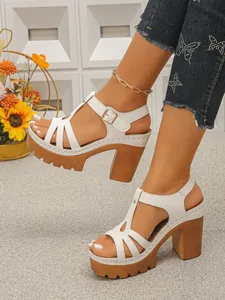Detailopname van witte plateausandalen met grove houtlook hakken en een kartelzool.