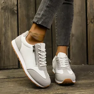 Close-up of white and grey women's casual sneakers featuring a stylish side zipper detail