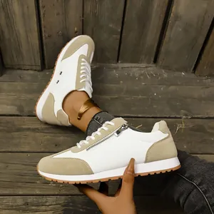 Detail view of women's beige German trainer sneakers with side zipper on wooden background.