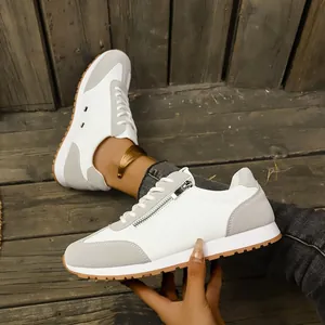 Macro detail view of white and grey sneakers with stylish side zipper and gum sole