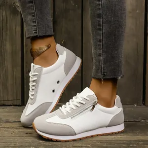 Detailed view of stylish grey and white women's casual sneakers worn by a model