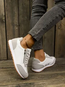 Detail view of stylish women's grey and white lightweight casual sneakers on model