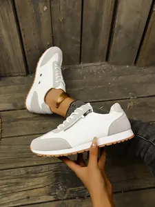 Detailed view of women's grey and white sneakers with side zipper and rubber sole