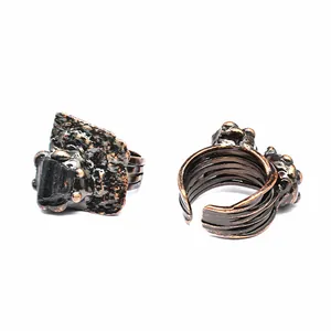 Detailed macro view of two vintage bronze-finish open rings with raw black stones.