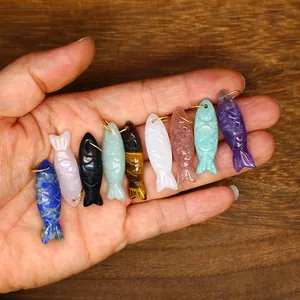 Detailed view of various natural stone pendants meticulously carved into small fish shapes.