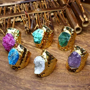 Close-up of natural raw crystal rings with textured wide golden bands on wood