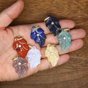 Leaf-shaped natural stone pendants with zircon inlay in various colors shown in palm.
