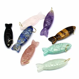 Detail view showing variety of carved natural stone fish pendants with gold rings